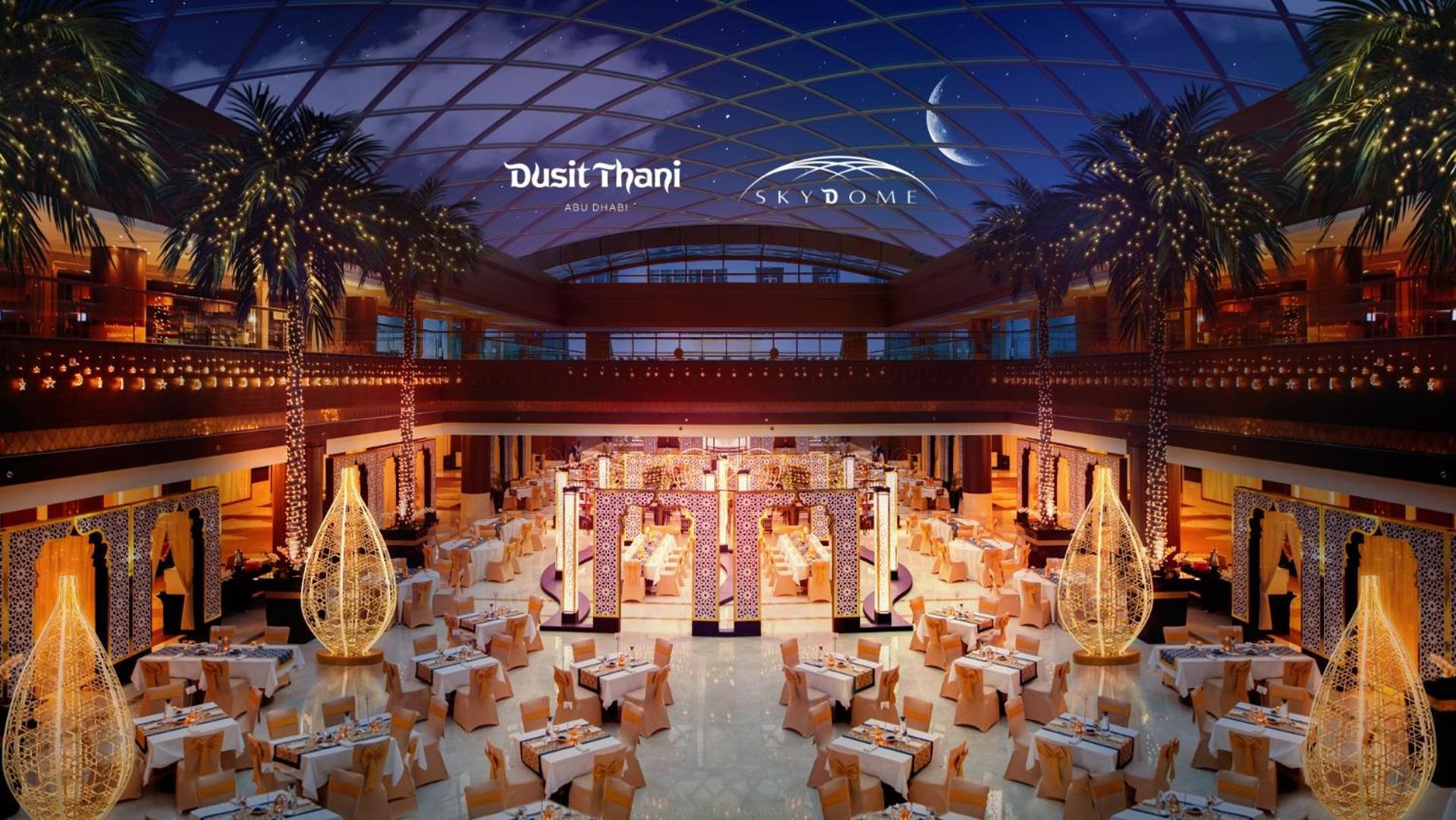 Dusit Thani Абу-Даби Экстерьер фото The image depicts a luxurious dining space within a large venue, likely associated with Dusit Thani and Skydome. The interior features elegant decorations, including a spacious layout with numerous tables set for dining. Elegant lighting fixtures cre